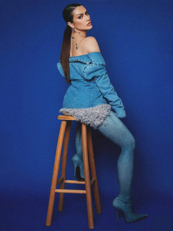 A atriz, cantora e escritora Cleo Pires posa para um retrato sentada em um banco de madeira