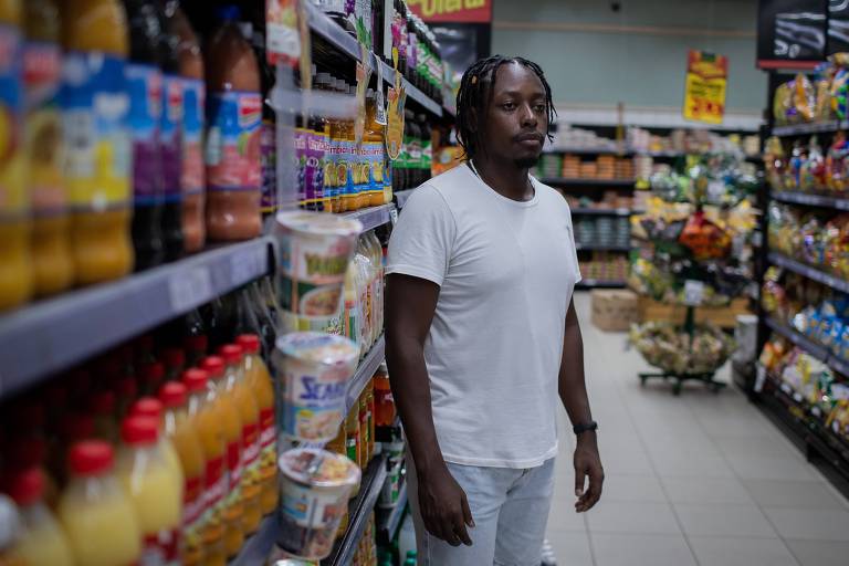 Homem negro vestido de branco no corredor de um supermercado