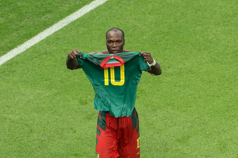 Segurando sua camisa e mostrado a parrte de trás dela, com o número dez, o camaronês Aboubakar festeja o gol que marcou no Brasil no estádio Lusail, no Qatar