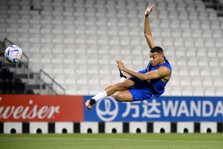 Suspenso no ar, o atacante Mbappé dá um voleio em treino da França no estádio Jassim-bin-Hamad, em Doha, no Qatar