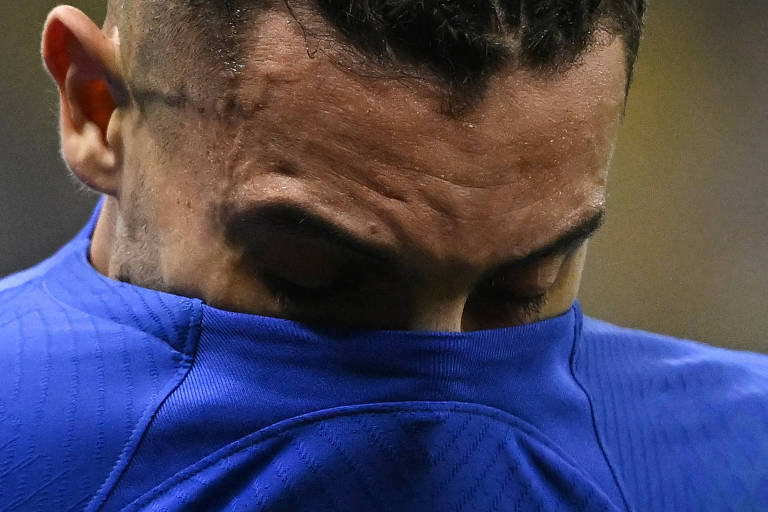O lateral Alex Telles cobre parcialmente o rosto com a camisa azul da seleção brasileira depois de sentir o joelho em Brasil contra Camarões, no estádio Lusail, no Qatar