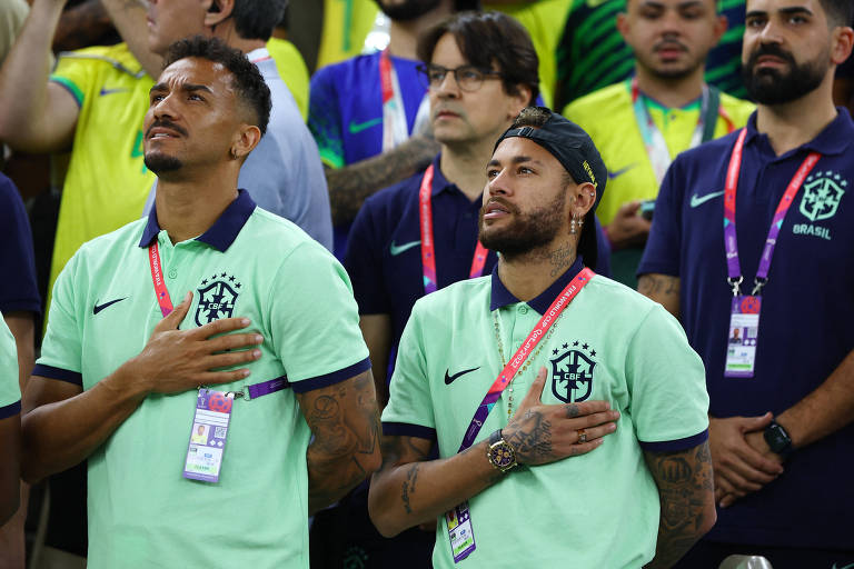Com a mão direita no lado esquerdo do peito, Danilo e Neymar, fora do jogo por contusão, cantam o hino do Brasil antes da partida contra Camarões na Copa do Qatar