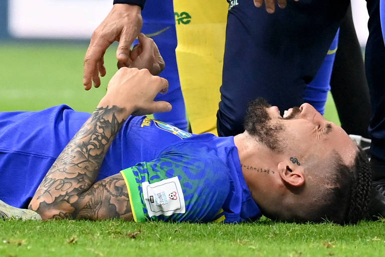 Deitano no gramado, Alex Telles geme depois da lesão no joelho direito na partida do Brasil contra Camarões no estádio de Lusail, no Qatar, na Copa do Mundo