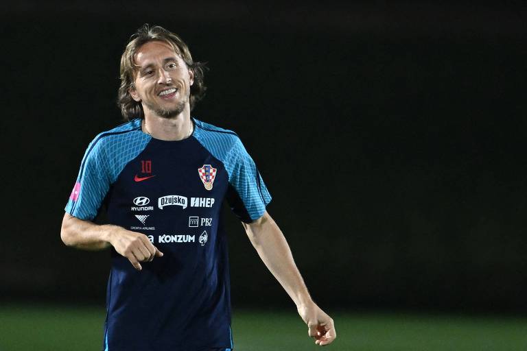 Com camisa azul escura com as mangas em azul claro, o capitão da Croácia, Modric, sorri em treino da equipe em Doha, durante a Copa no Qatar