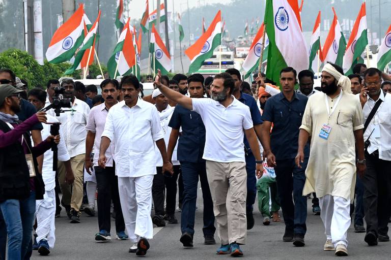 Pessoas caminham carregando bandeiras da Índia