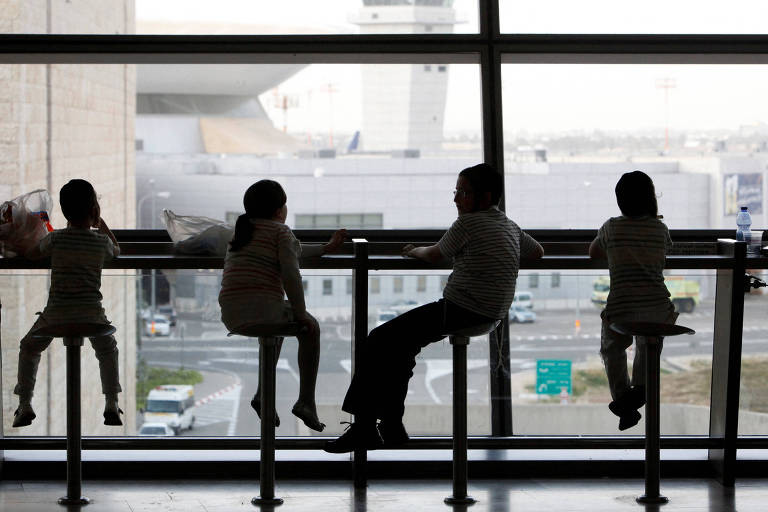 Crianças em frente a uma área de vidros que dá para área externa do aeroporto 