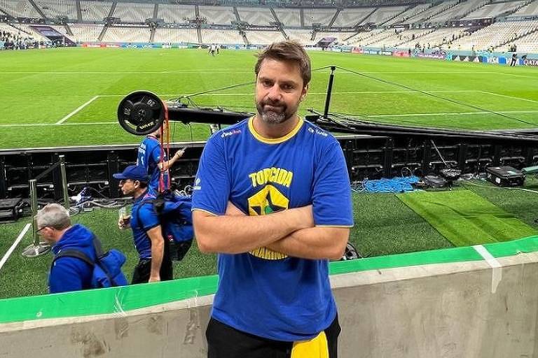 Em foto colorida, homem de camisa azul posa em estádio