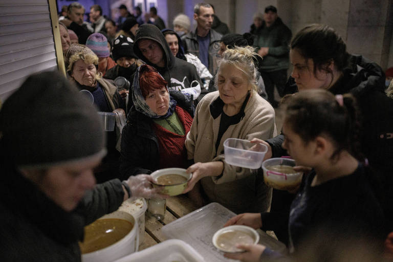 Voluntários distribuem comida em estação de metrô usada como abrigo antiaéreo no norte de Kharkiv, na Ucrânia