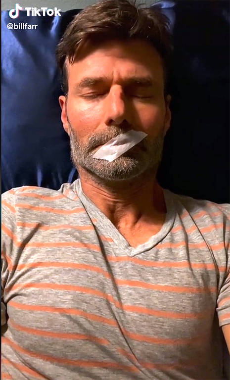 Homem deitado com fita tapando a boca