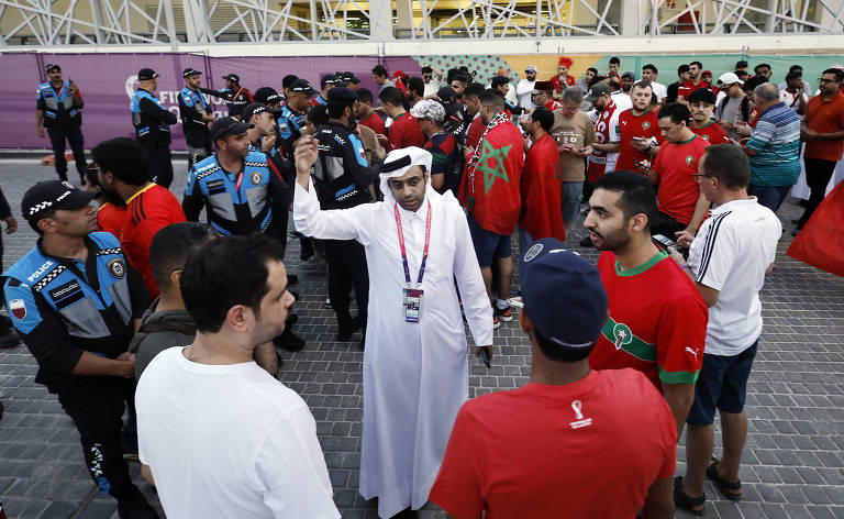 Funcionário da organização conversa com torcedores marroquinos antes do jogo contra a Espanha, em Al Rayyan