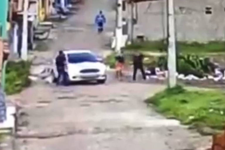 Imagem de câmera de segurança mostra carro em rua com homens de preto abordando homem