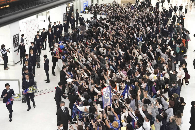 Multidão acompanha o desembarque da seleção do Japão no aeroporto de Narita