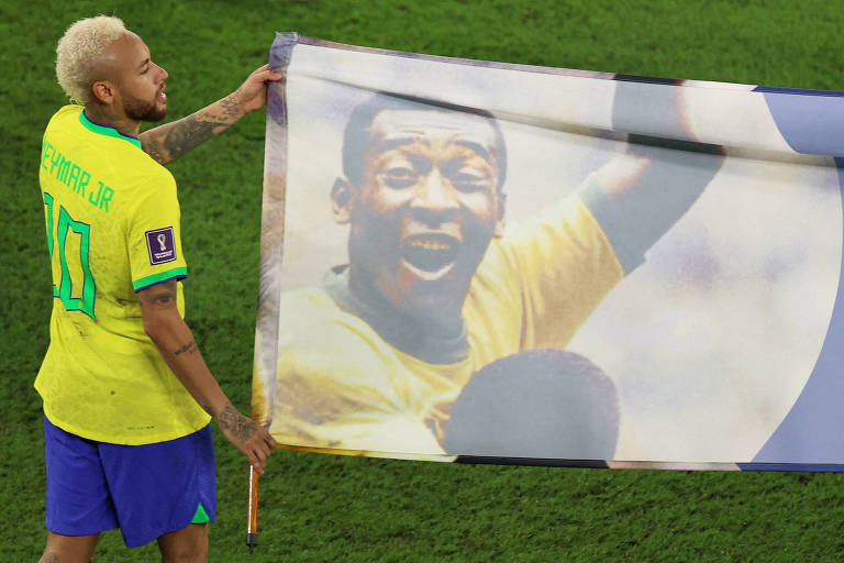 Neymar ao lado de bandeira que homenageia Pelé, que está comemorando um gol na imagem, depois do jogo contra a Coreia do Sul no estádio 974, em Doha