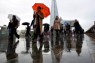 FILE PHOTO: Commuters walk across London Bridge toward the financial district, in London