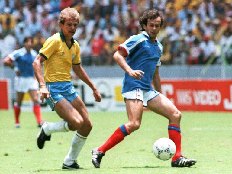 Alemão marca Platini, que conduz a bola em Guadalajara na partida em que o Brasil perdeu nos pênaltis para a França na Copa do México, 36 anos atrás