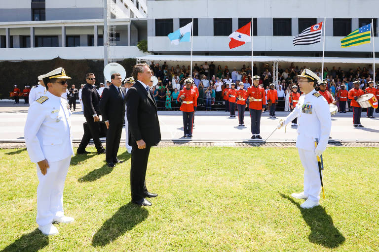 De pé, o presidente Jair Bolsonaro participa de formatura de oficiais na Escola Naval, no Rio, neste sábado