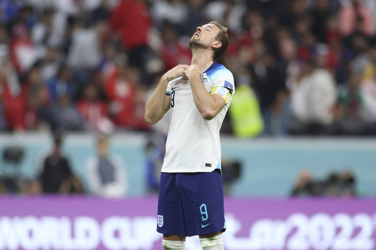 Com camisa branca, calção azul escuro, a cabeça inclinada para trás e os olhos fechados, o capitão da Inglaterra, Harry Kane, lamenta a eliminação ante a França nas quartas de final da Copa do Qatar, no estádio Al Bayt, em Al Khor 