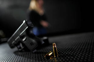 A pistol lies in front of shooter Jacqueline Neves at the shooting range, in Brasilia