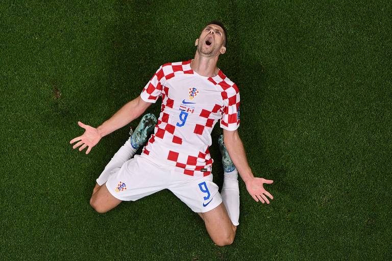 O centroavante croata Andrej Kramaric comemora, ajoelhado e berrando enquanto olha para cima,  ao fazer seu 1º gol contra o Canadá, no estádio Khalifa, na Copa no Qatar