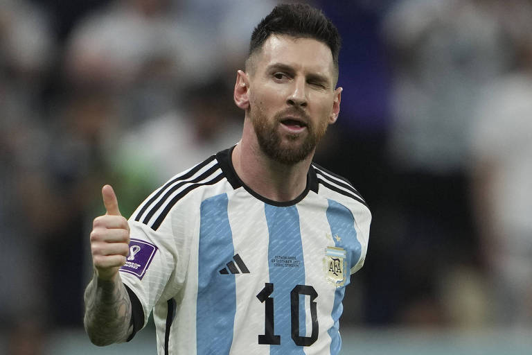 Imagem colorida mostra o argentino Messi, do tronco para cima, fazendo o sinal de positivo com a mão direita e piscando o olho esquerdo.
