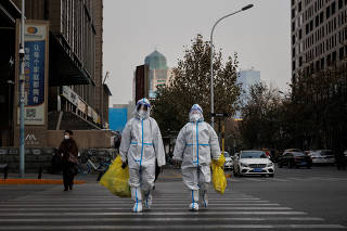 FILE PHOTO: Pandemic prevention workers in protective suits cross a street as coronavirus disease (COVID-19) outbreaks continue in Beijing