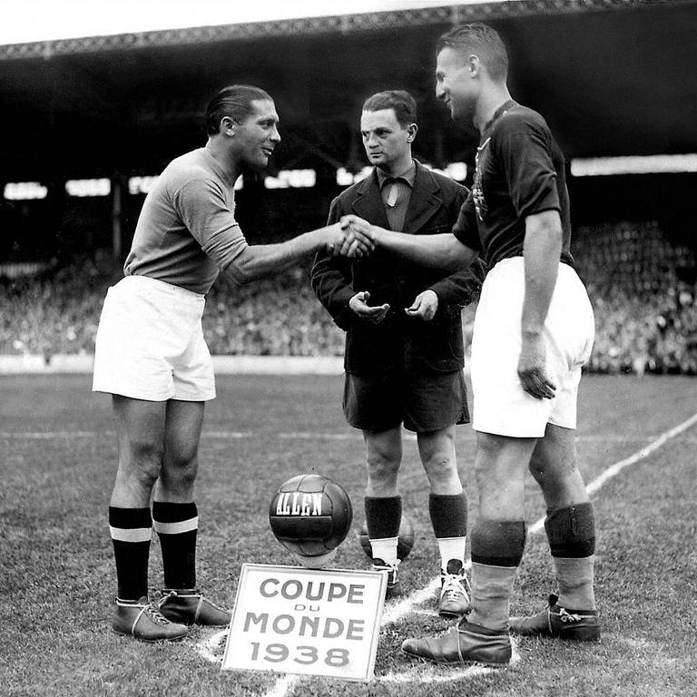 Observados pelo árbitro Georges Capdeville, o italiano Giuseppe Meazza, capitão da Itália, cumprimenta o húngaro Gyorgy Sarosi antes da decisão da Copa de 1938, em Colombes (Grande Paris)