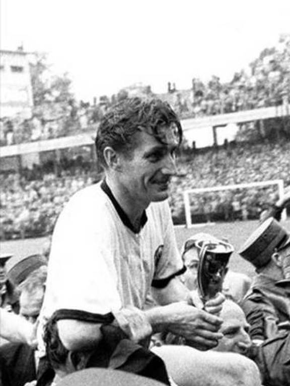 O alemão Fritz Walter, capitão da Alemanha Ocidental, segura a Taça Jules Rimet enquanto é carregado por torcedores depois da vitória sobre a Hungria por 3 a 2 na decisão da Copa de 1954, no estádio Wankdorf, em Berna, na Suíça
