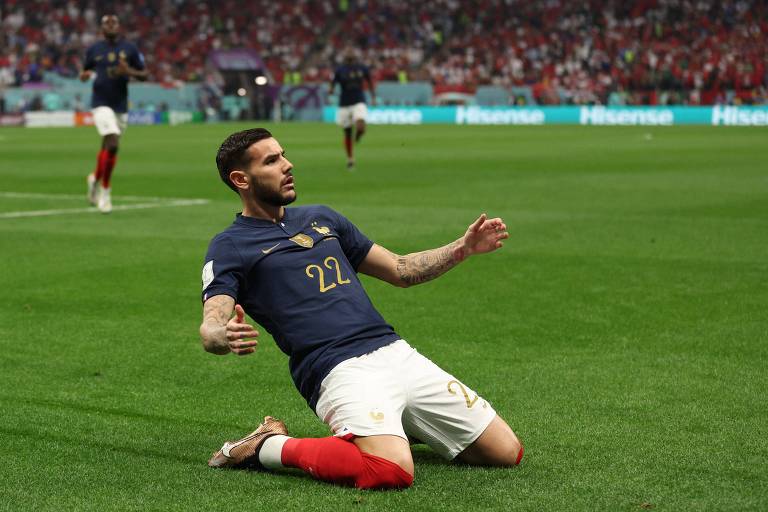 De camisa azul, calção branco e meiões vermelhos, o lateral esquerdo Theo Hernández, da França, desliza de joelhos para comemorar seu gol, o primeiro na vitória por 2 a 0 sobre Marrocos na semifinal da Copa do Qatar