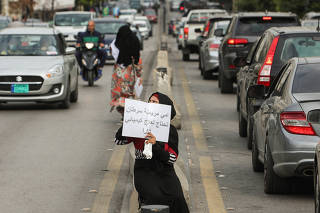 A beggar holds a sign reading 
