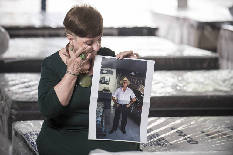 A foto mostra a empresária Eliana Reis segurando quadro com foto de seu marido, José Osvaldo Faria, que morreu depois de beber cerveja produzida pela Backer.