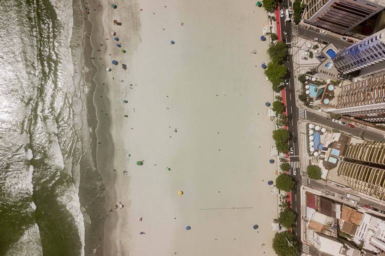 foto aérea de faixa de areia, ladeada por mar e prédios