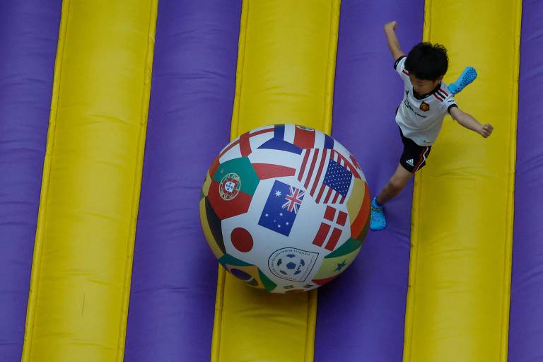 Uma criança brinca com uma bola de futebol enorme com as bandeiras dos países da Copa do Mundo em um shopping em Doha