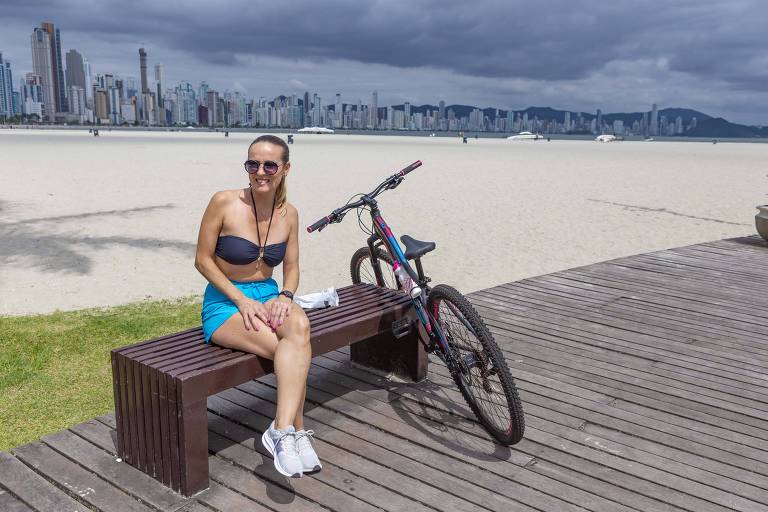 mulher sentada em banco e bicicleta com praia ao fundo