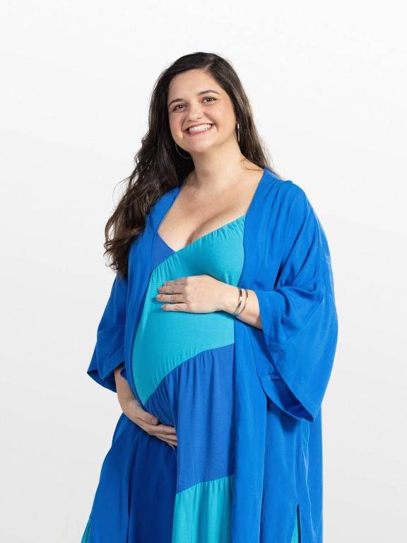 Mulher grávida, de cabelos longos castanhos, usando vestido azul