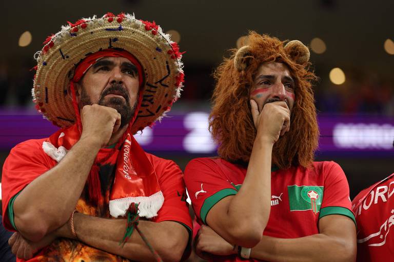 Dois torcedores de Marrocos, u com chapeú estilo mexicano e outro com um que imita um leão, na partida em que a seleção africana perdeu por 2 a 0 para a França em semifinal da Copa no Qatar, no estádio Al Bayt, em Al Khor