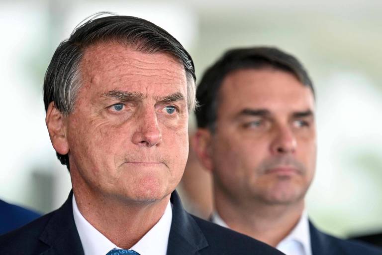 O senador Flávio Bolsonaro (PL) atrás do presidente Jair Bolsonaro em agenda no Palácio do Planalto