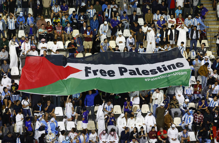Torcedores exibem uma bandeira da Palestina com a mensagem 'Palestina Livre' nas arquibancadas