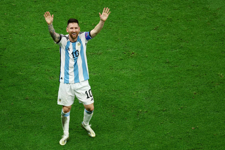Com os braços erguidos e sorrindo, Messi comemora no gramado do estádio Lusail, no Qatar, a conquista da Copa do Mundo