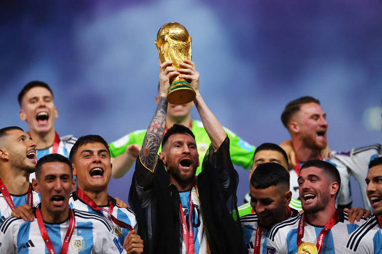 Cercado por colegas da seleção argentina, Messi ergue a Taça Fifa do estádio Lusail, no Qatar