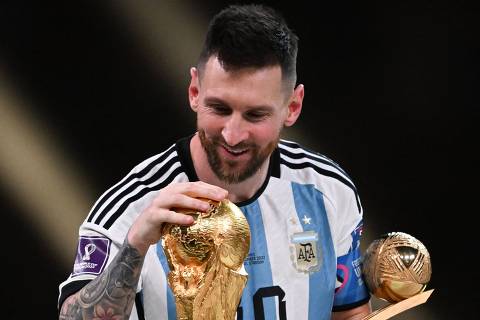 Argentina's captain and forward #10 Lionel Messi smiles as he touches the FIFA World Cup Trophy during the trophy ceremony after Argentina won the Qatar 2022 World Cup final football match between Argentina and France at Lusail Stadium in Lusail, north of Doha on December 18, 2022. (Photo by Kirill KUDRYAVTSEV / AFP)