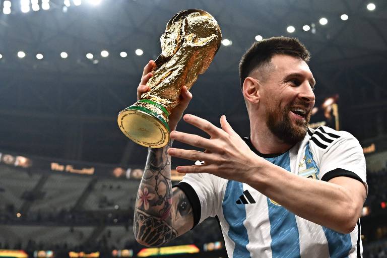 Lionel Messi é carregado dentro do estádio, sem largar do troféu da Copa do Mundo