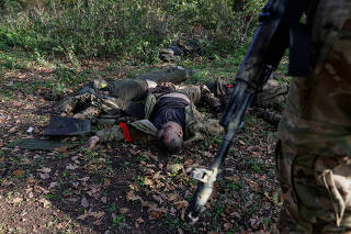 Ukrainian service member stands next to the bodies of dead Russian soldiers in Donetsk region