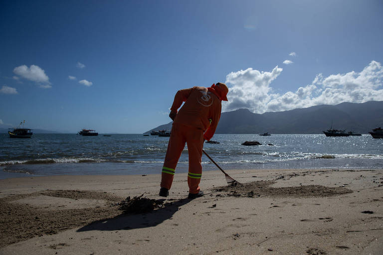 Funcionário da Prefeitura de São Sebastião trabalha na limpeza da praia de São Francisco, classificada como péssima para banho