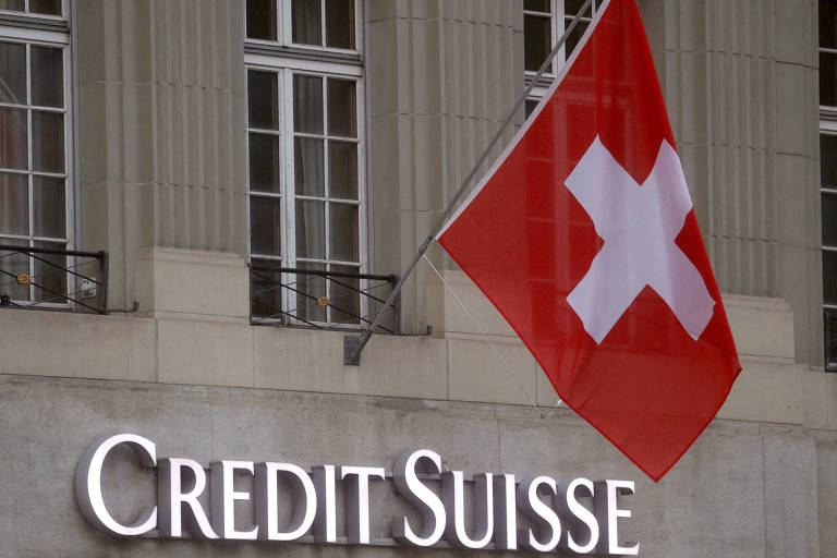 Bandeira da Suíça tremula acima do logo do banco Credit Suisse em frente a uma filial em Berna