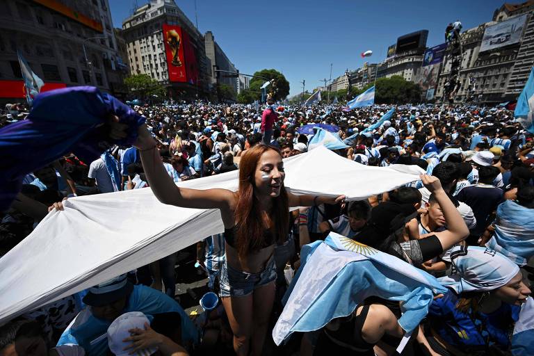 Torcedora da Argentina se destaca entre milhares de pessoas festejando, sob forte calor, a conquista da Copa do Mundo por Messi e companhia na região do Obelisco, em Buenos Aires