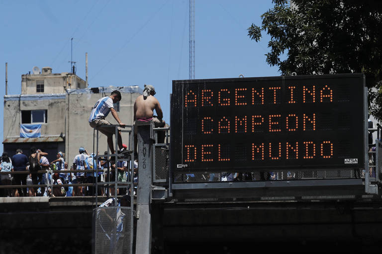 Torcedores sobem nas casas e em postes para acompanharem a passagem da seleção argentina em Buenos Aires