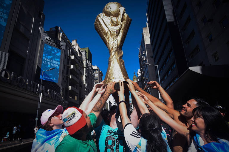 Na parada da vitória, no centro de Buenos Aires, torcedores erguem réplica gigante da Taça Fifa, troféu entregue domingo à seleção argentina, atual campeã da Copa do Mundo