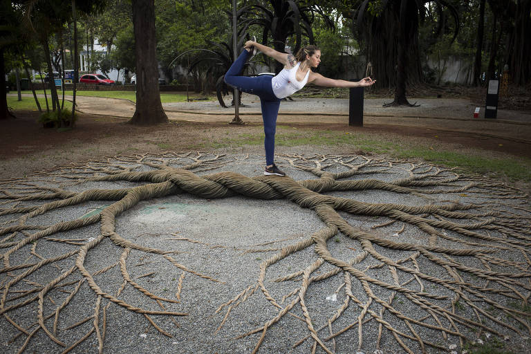 Mulher em pose de yoga acima de raízes de árvore