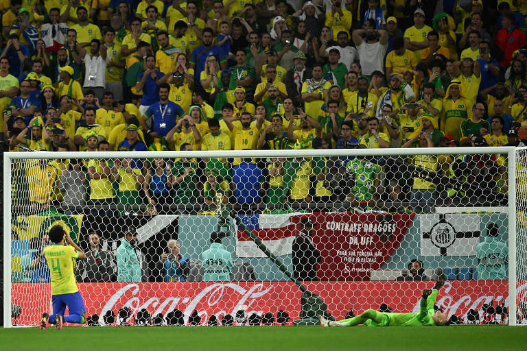 O brasileiro Marquinhos lamenta, ajoelhado, erro na disputa de pênaltis contra a Croácia nas quartas de final da Copa no Qatar; diante dele, deitado, o goleiro Livakovic comemora