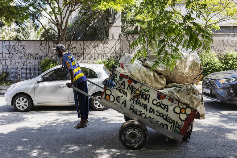 O catador Almirando Barbosa dos Santos, que trabalha com reciclagem há mais de 20 anos, puxa sua carroça carregada na zona oeste de São Paulo